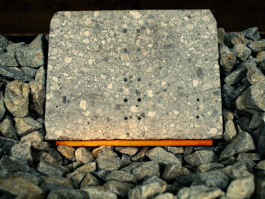 Concrete block on an orange vibration isolator (Sleeper Pad SL 7000) in the ballast. Concrete block on an orange vibration isolator (Sleeper Pad SL 7000) in the ballast.